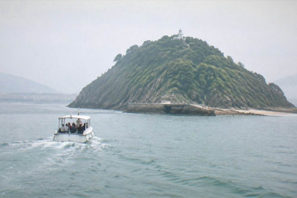 A small boat crossing La Concha bay with Santa Clara island behind