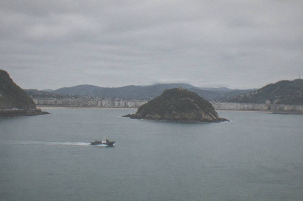 A small boat crossing the flat water of La Concha bay towards the island