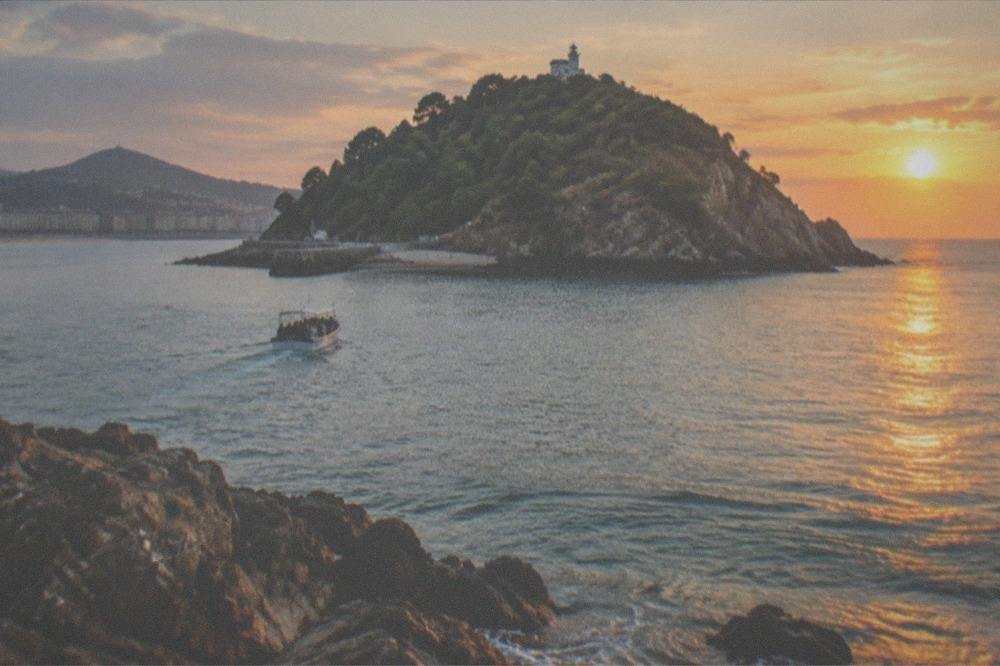 Sunset light on the water of the bay with the island's rocks in the foreground