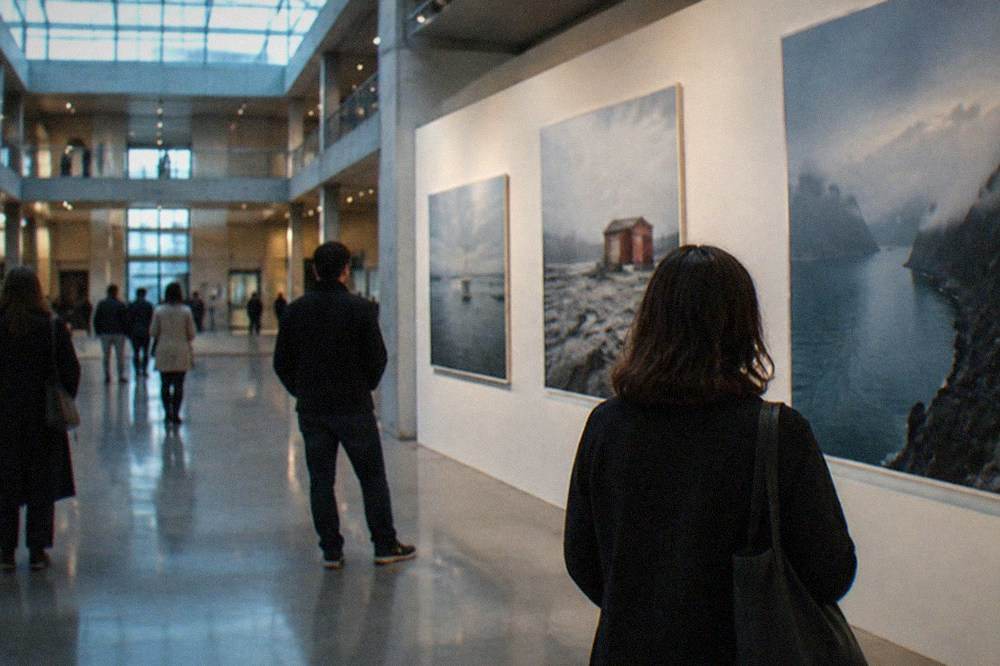 Visitors looking at large contemporary photographs on a gallery wall inside a museum hall