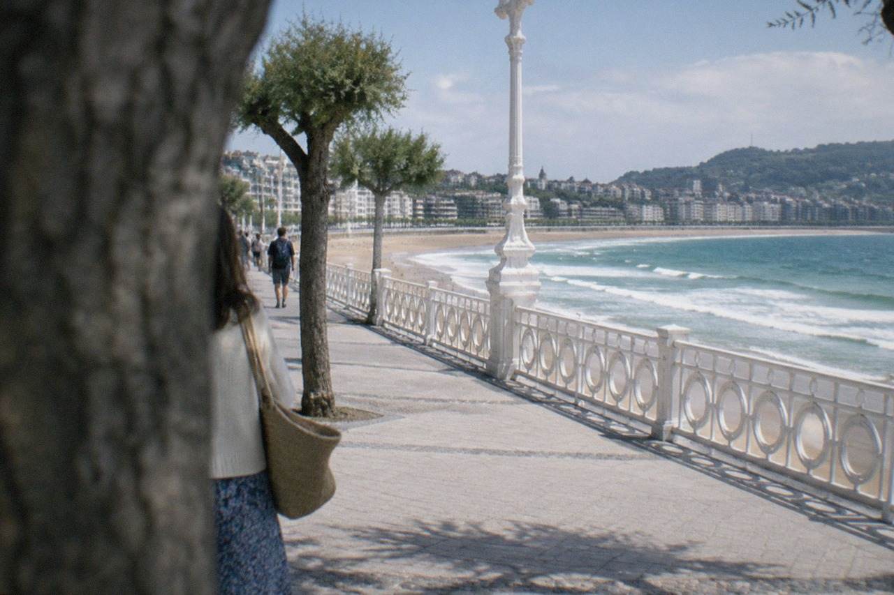 Wide sandy beach with rolling waves and a promenade backed by apartment buildings