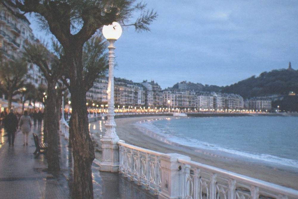 Apartment buildings and cafés along a seafront promenade in the evening