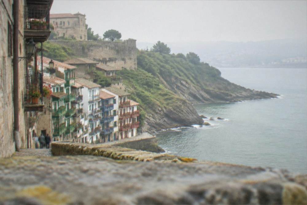 Steep layered rock cliffs meeting the sea along a green headland