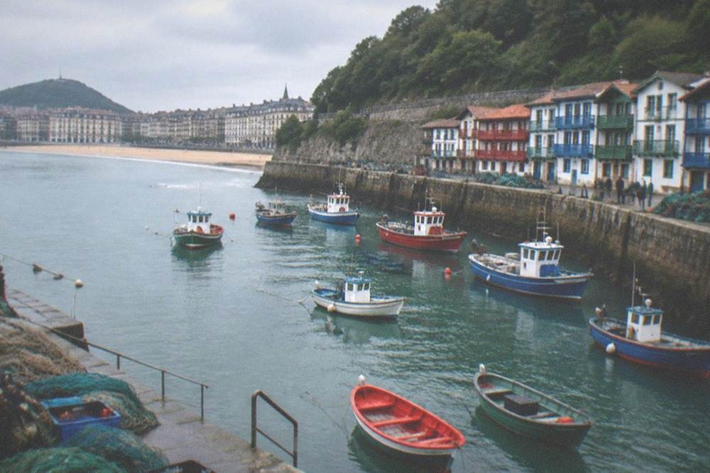 A sheltered bay with a sandy town beach, fishing boats moored in a small harbour and houses with wooden shutters
