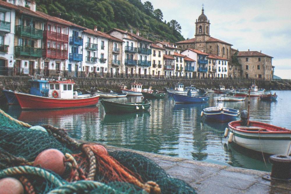 A fishing harbour with stone houses and a church tower, in a Basque coastal town