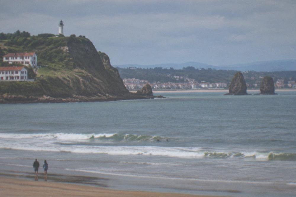A rocky Atlantic headland with a lighthouse above green cliffs