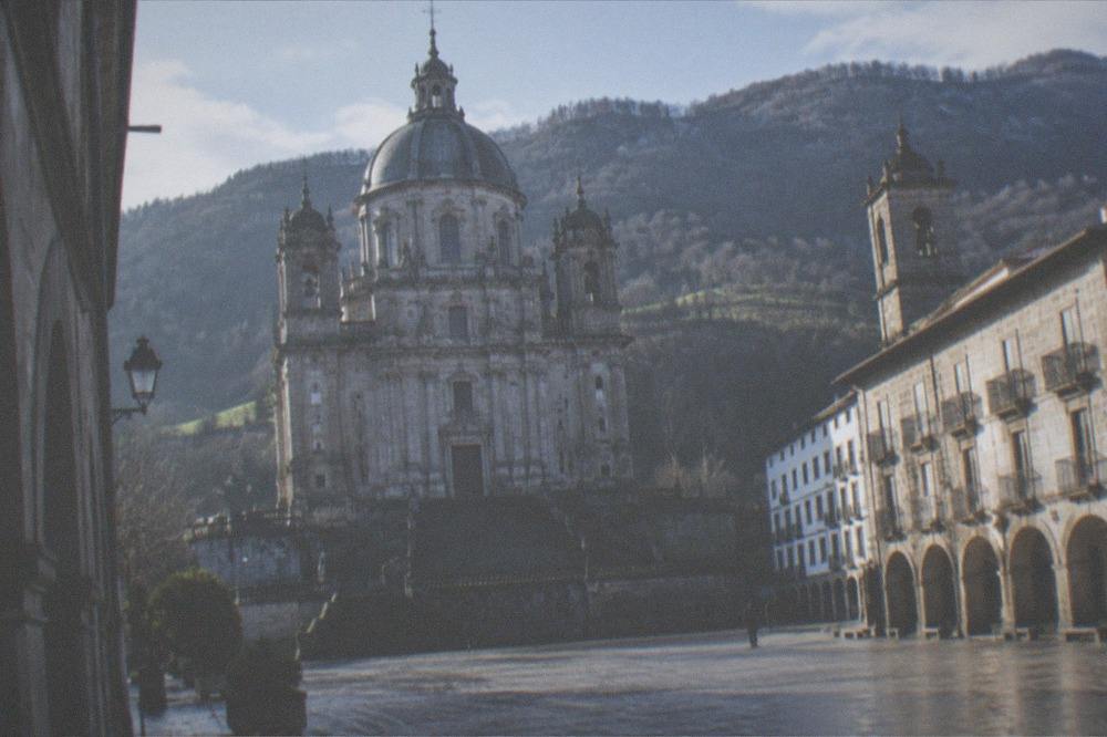 A small Basque town square with stone buildings, arcades and a church tower in inland Gipuzkoa