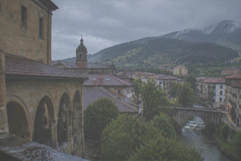 View over the rooftops of Onati toward green hills under a mixed sky