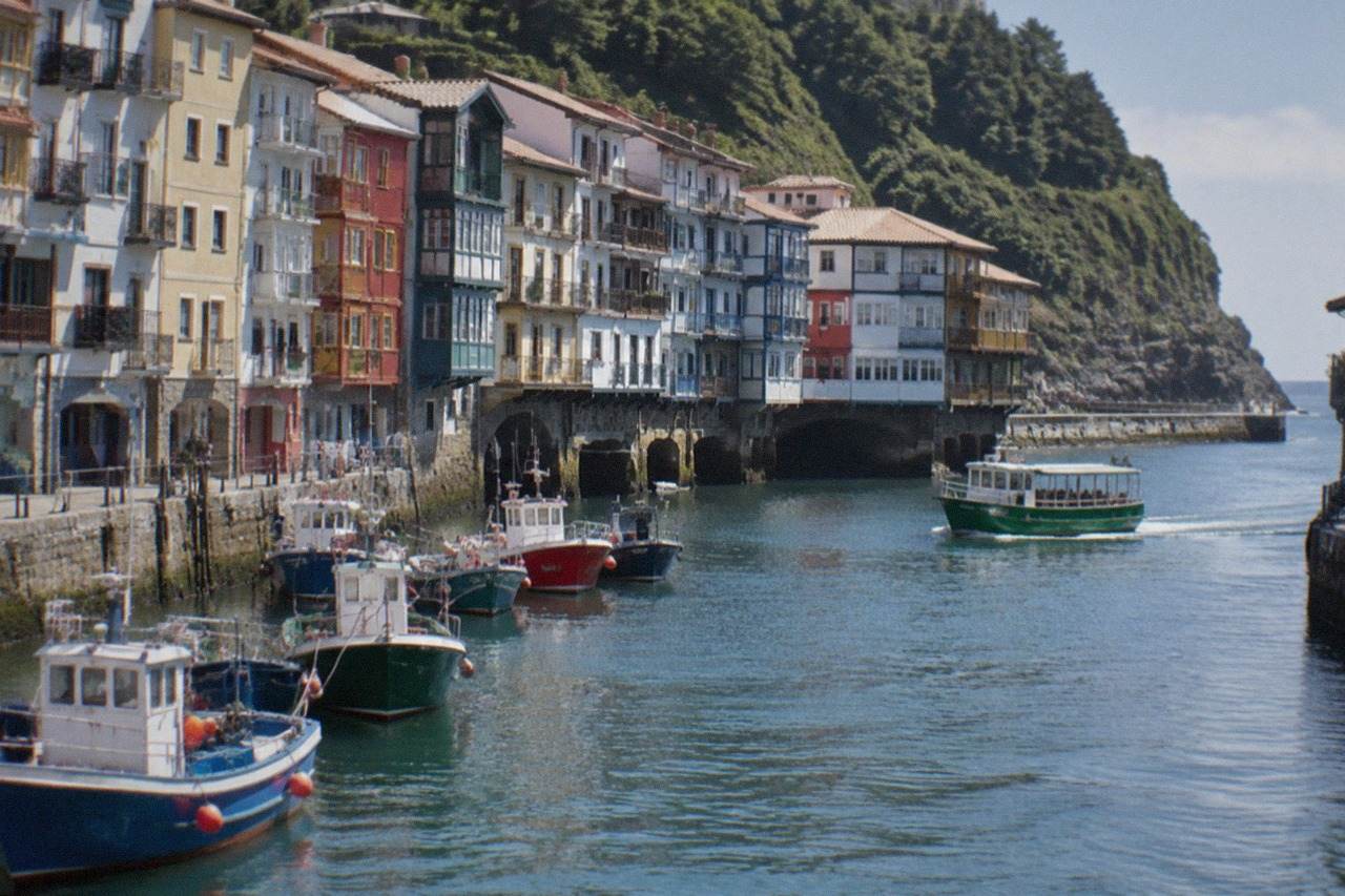 Colourful harbour buildings along the waterfront of Pasai Donibane with fishing boats moored in the narrow bay