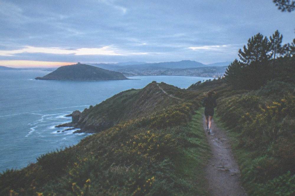 Coastal footpath along the green ridge of Monte Ulia with the sea and cliffs below