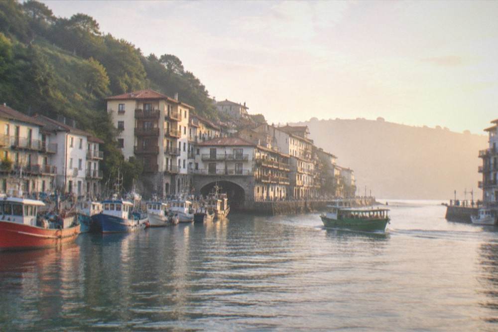 Fishing boats and harbour buildings of Pasaia seen from the water at golden hour