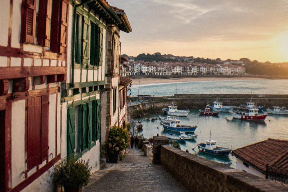 Old timber-fronted houses in red and green above a narrow street in the old town of Saint-Jean-de-Luz