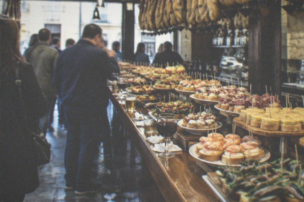 Trays of small skewered pintxos displayed on a wooden bar counter