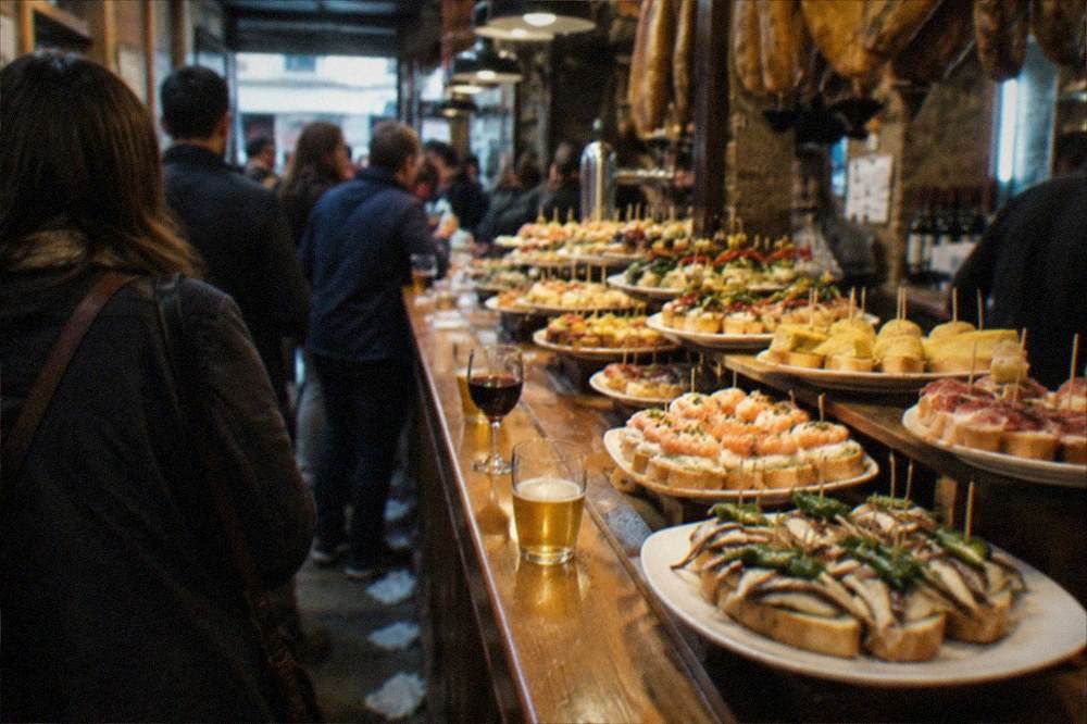 Pintxo bars with crowds at the counter in an Old Town street at night