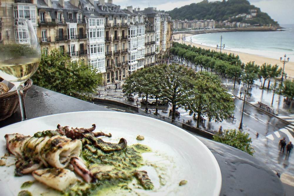 A plated dish of seafood with green sauce on a white ceramic plate