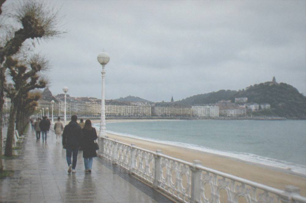People walking along an elegant seaside promenade beside a curved bay