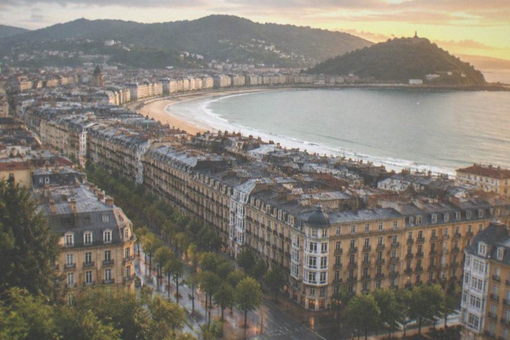 Aerial view of a dense city centre between green hills and a shell shaped bay