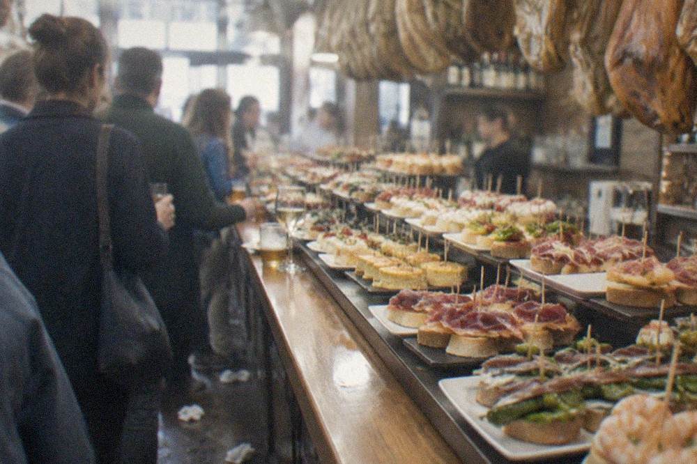 A pintxo bar counter covered with trays of small skewered dishes