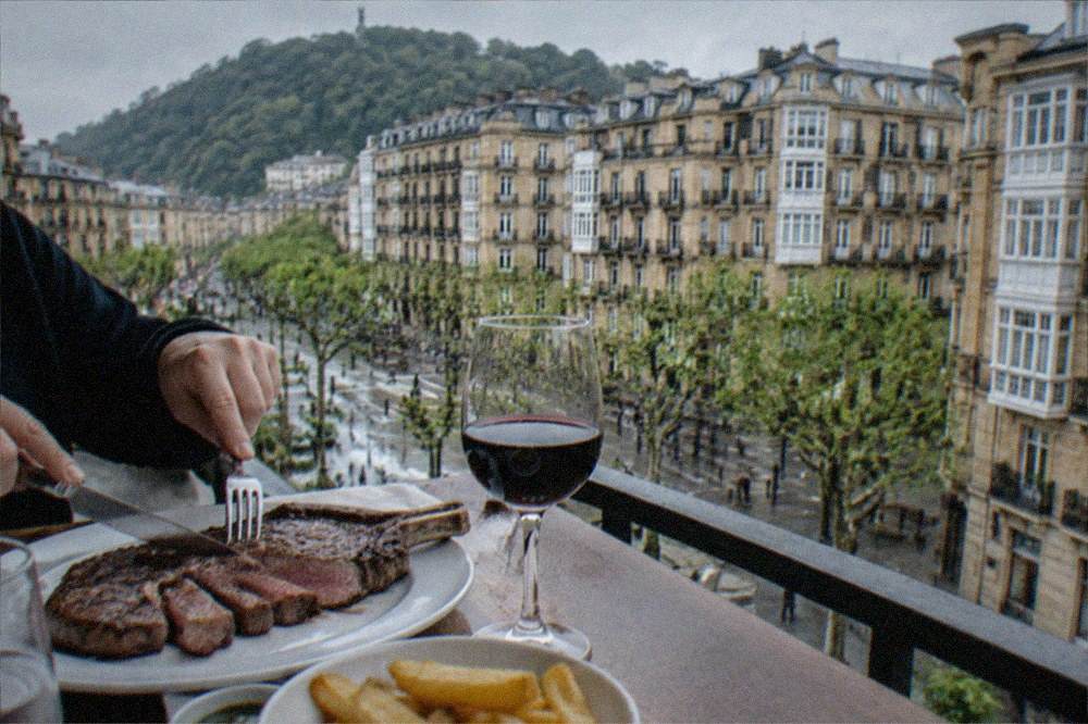 A grilled rib steak being sliced at a restaurant table in San Sebastián