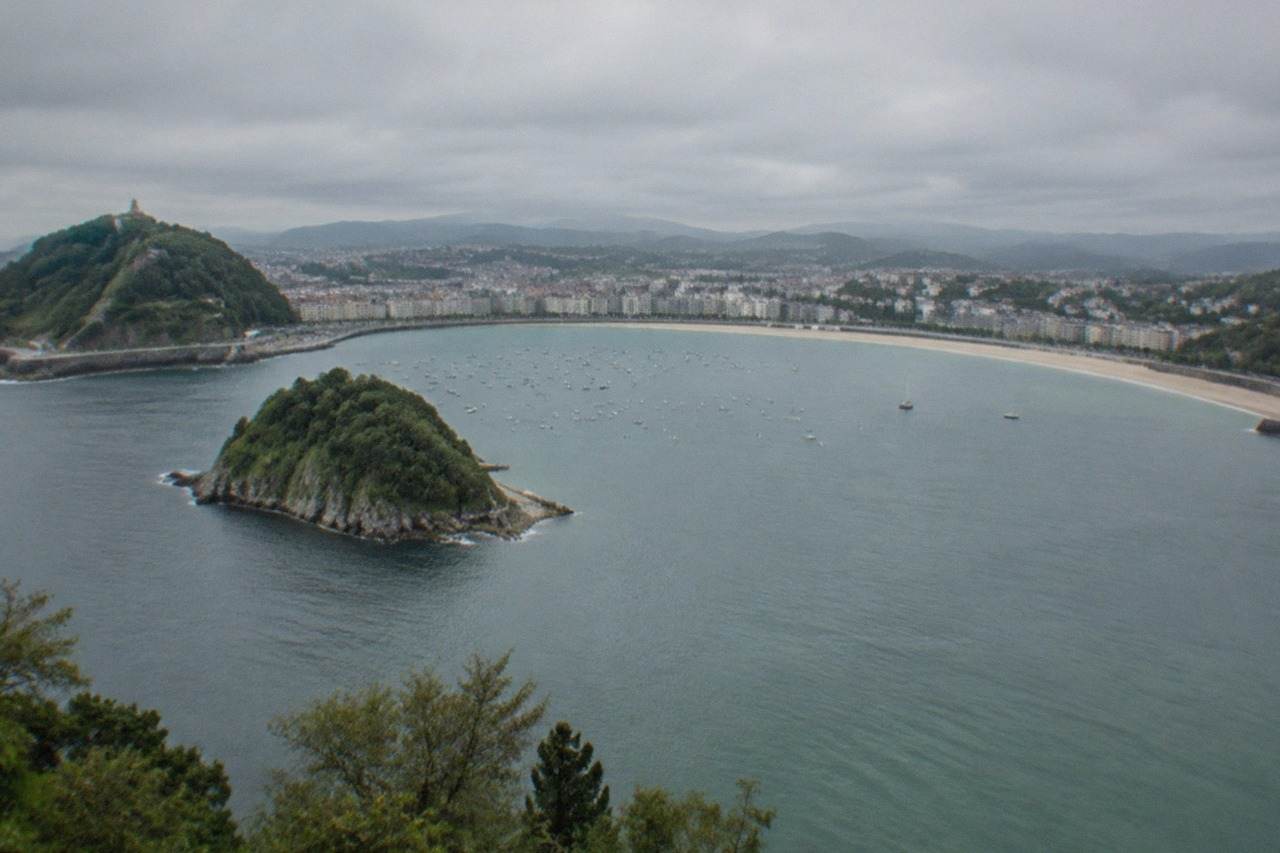 La Concha bay in San Sebastián seen from above, with the beach curving between two green hills