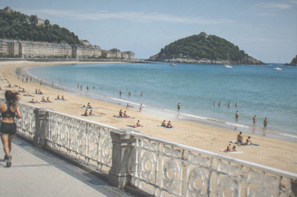 Swimmers and sunbathers on the sand of La Concha beach with calm water in the bay