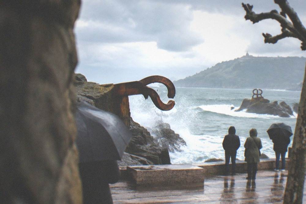 Waves breaking against the steel sculptures of the Peine del Viento on a grey winter day