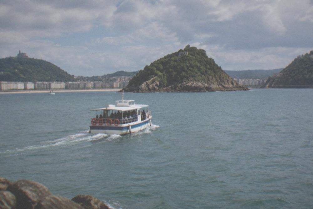 A small boat crossing La Concha bay toward Santa Clara island in summer light