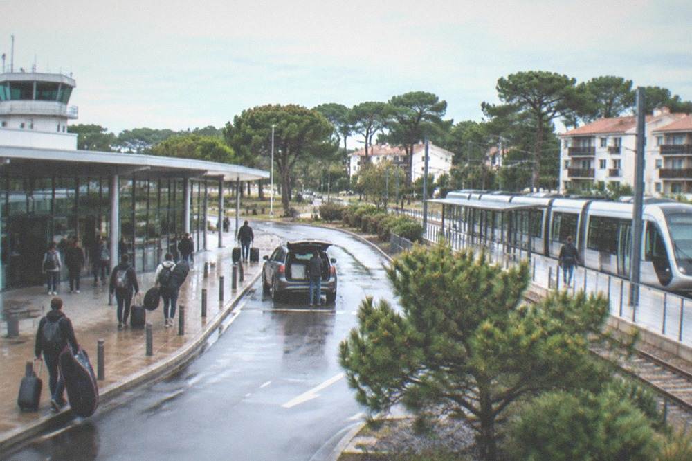 A modern light-rail train at a small station platform beside apartment buildings