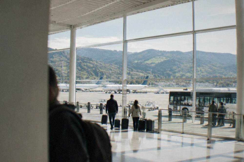 A view over an airport apron with parked aircraft and green mountains in the distance