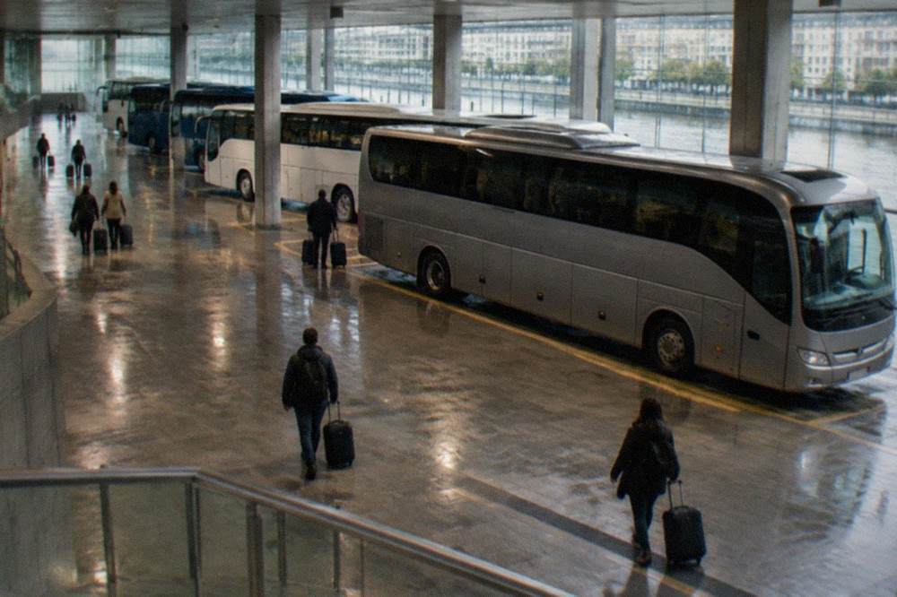 A long distance coach parked at an airport terminal curb under a grey sky