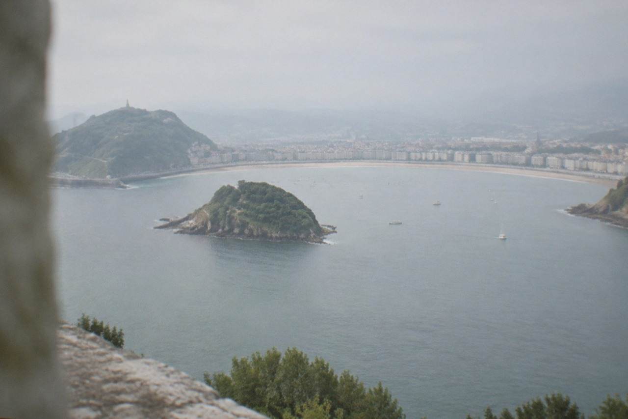 The curved bay of La Concha seen from above, with Santa Clara island in the middle and hills on both sides