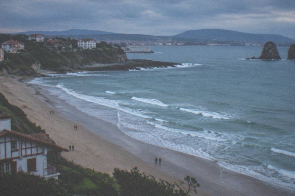 Waves breaking on a rocky coast under grey clouds with green cliffs