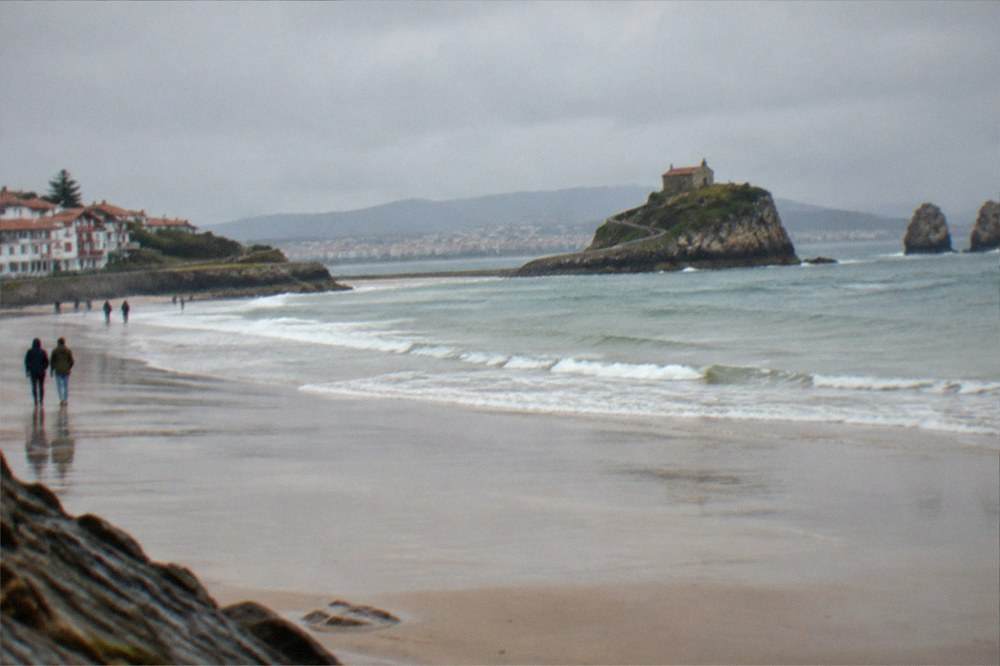 A stone hermitage on a rocky islet connected by a winding causeway above the sea
