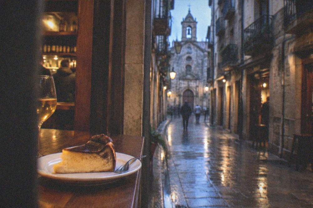 A golden slice of burnt Basque cheesecake on a small plate in a bar