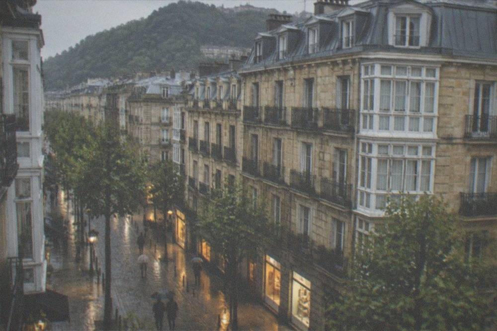 A rain-washed narrow street in the Old Town of San Sebastián with wet cobblestones reflecting shop lights
