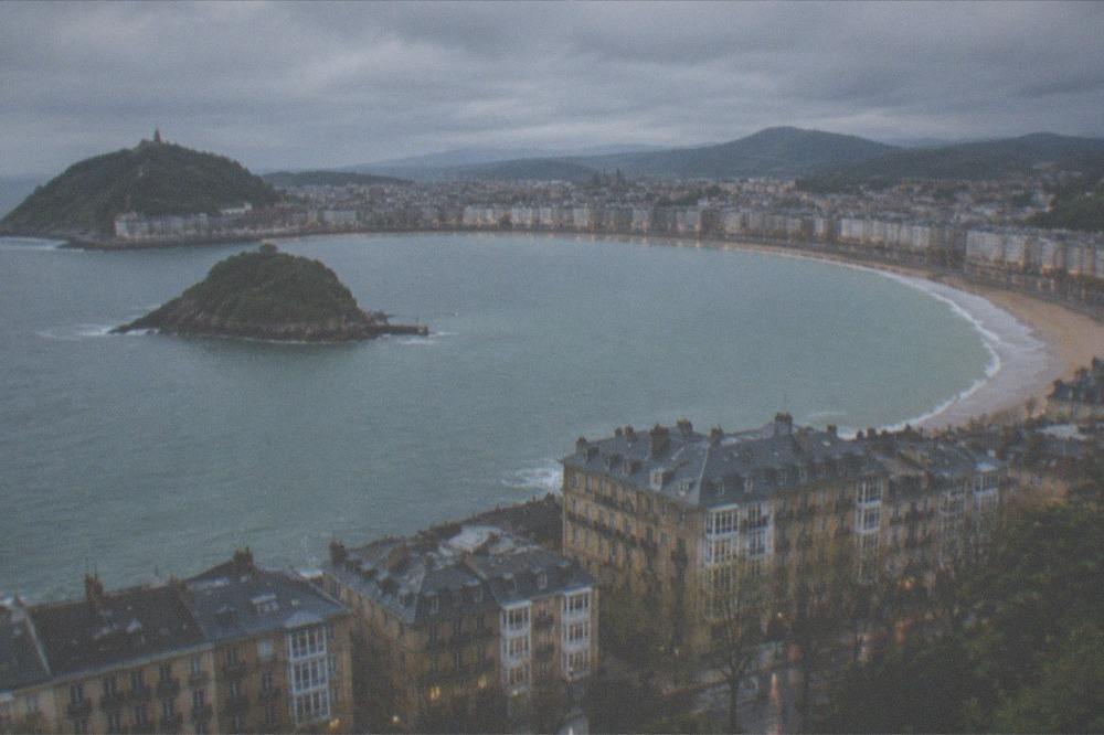 The bay of San Sebastián seen from above with the island, the beach and the dense city grid in evening light