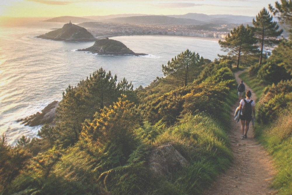 Green coastal hillside path in late summer light with the Bay of Biscay below