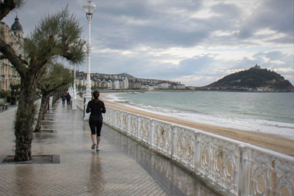 Long seaside promenade curving around a wide bay with an island offshore