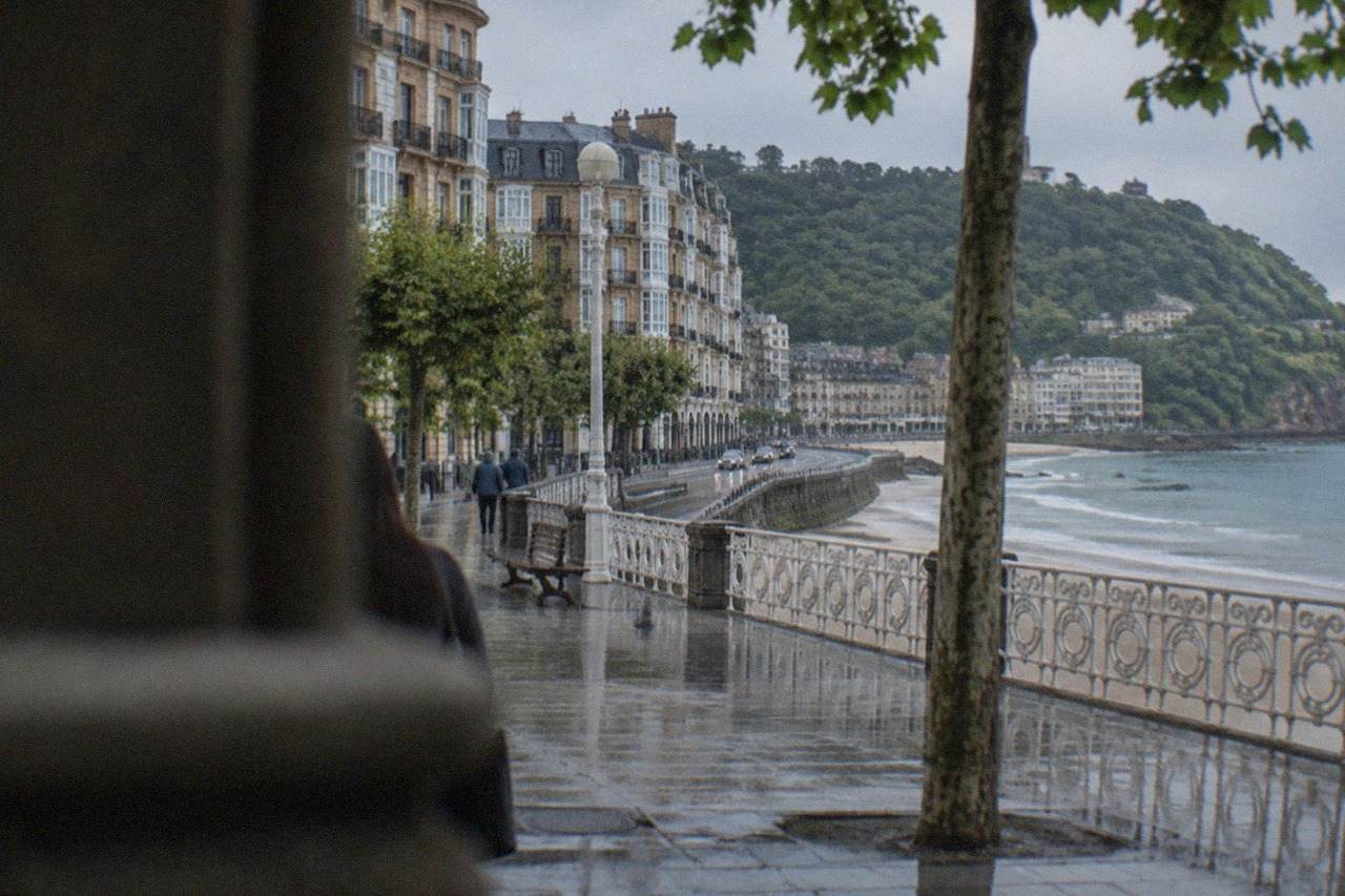 A coastal road curving along the Bay of Biscay toward San Sebastián with green hills above the sea