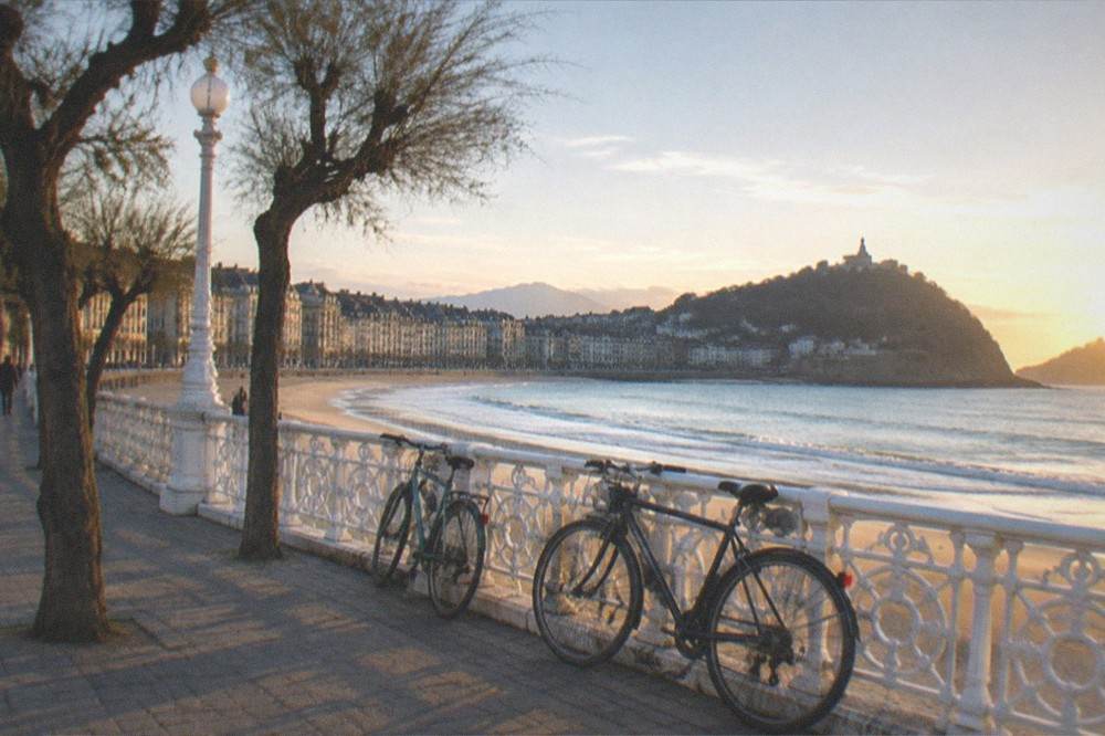 Bicycles parked by a promenade railing overlooking the bay at golden hour