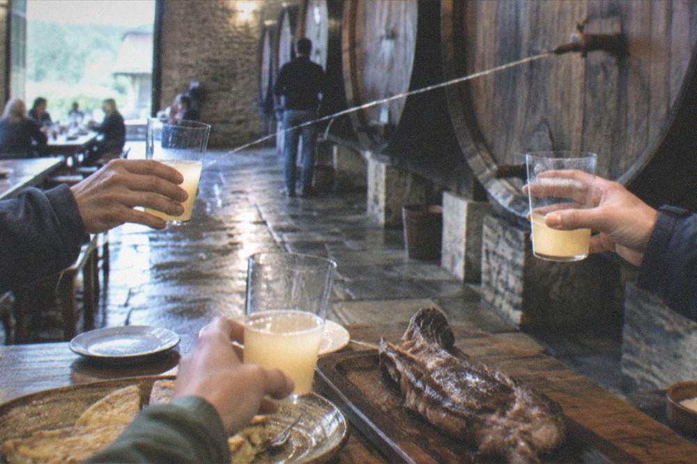 Glasses raised in a toast beside a wooden cider barrel