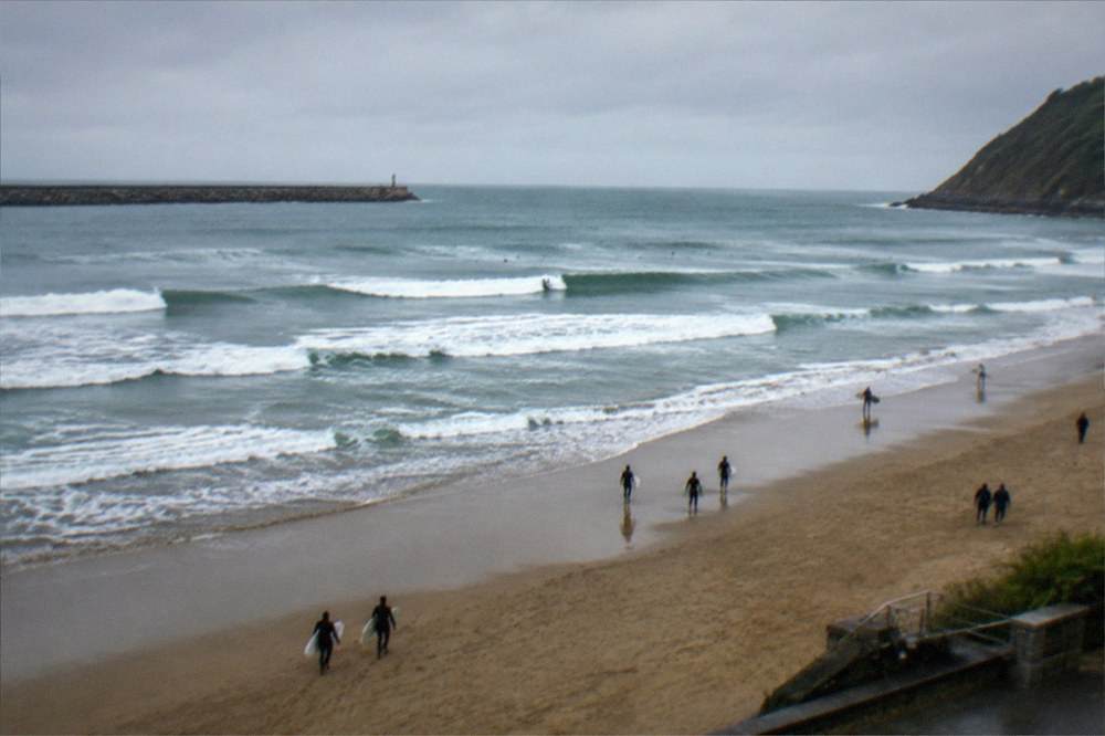 Surfers and walkers along Zurriola beach at the east end of the city