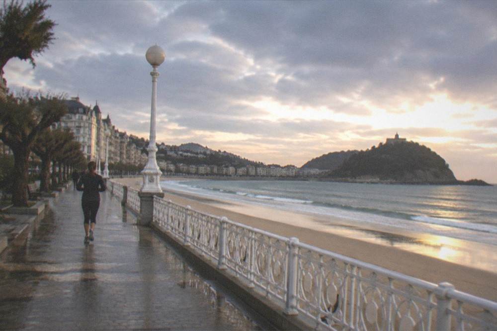 Evening light on La Concha beach with the promenade railing and island beyond