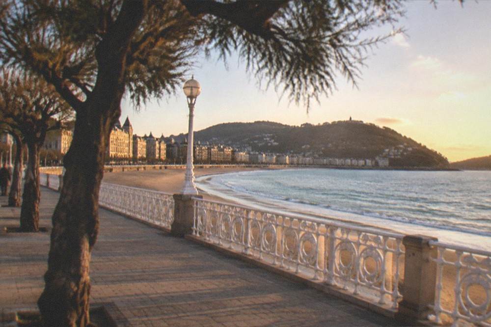 The promenade along La Concha with white railings, the beach and the bay curving away