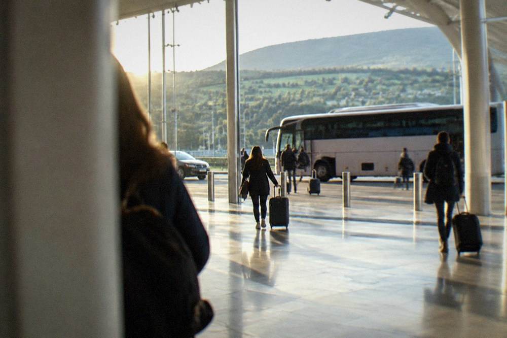 Coach parked at a regional airport terminal with hills behind it