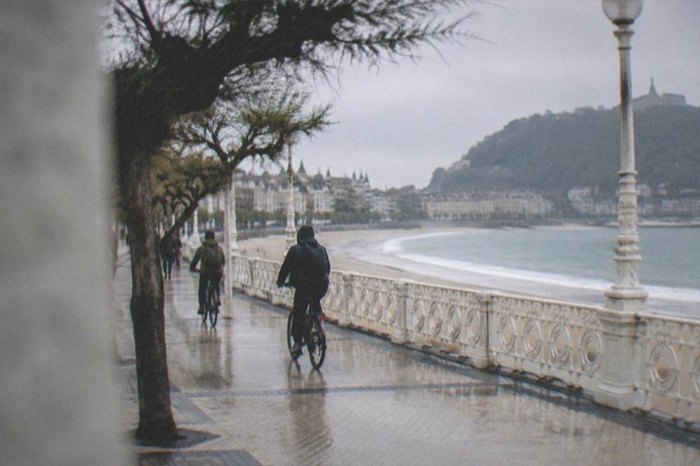 Cyclists riding along a beachfront promenade beside the bay