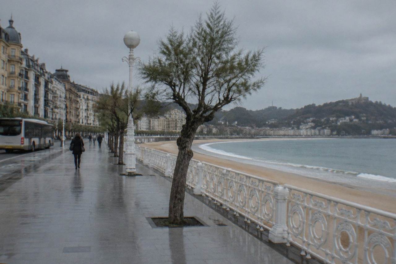 A city bus passing along the seafront promenade beside La Concha bay in San Sebastián