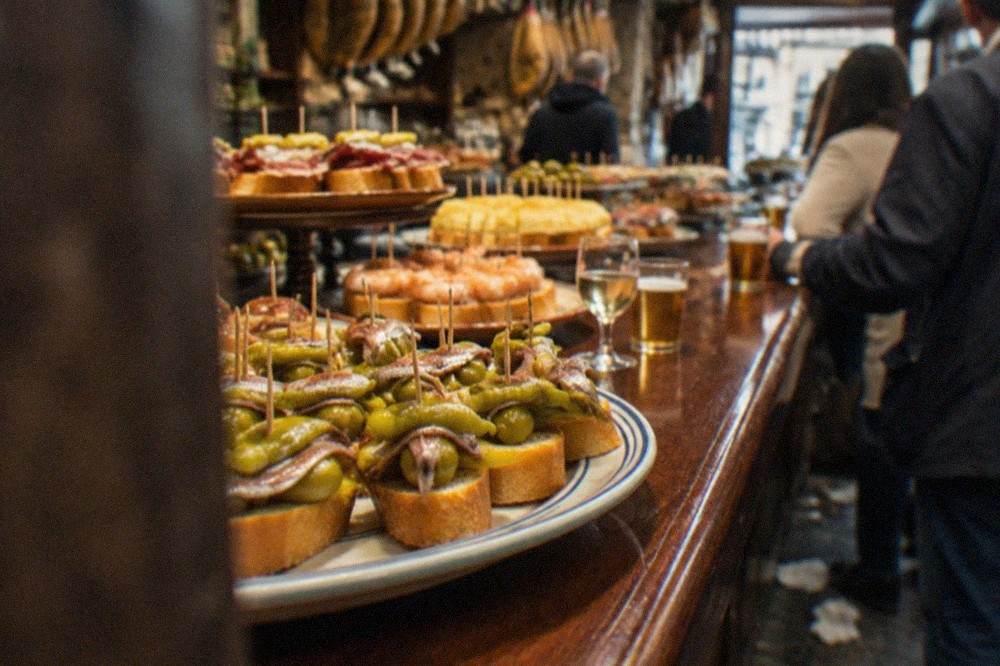 Close view of gilda pintxos lined up on a ceramic plate on a bar counter in the San Sebastián Old Town