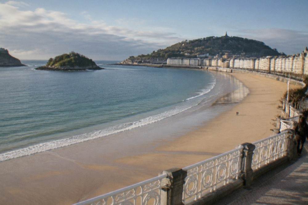 The long sandy curve of La Concha beach seen from the promenade with the seafront buildings behind