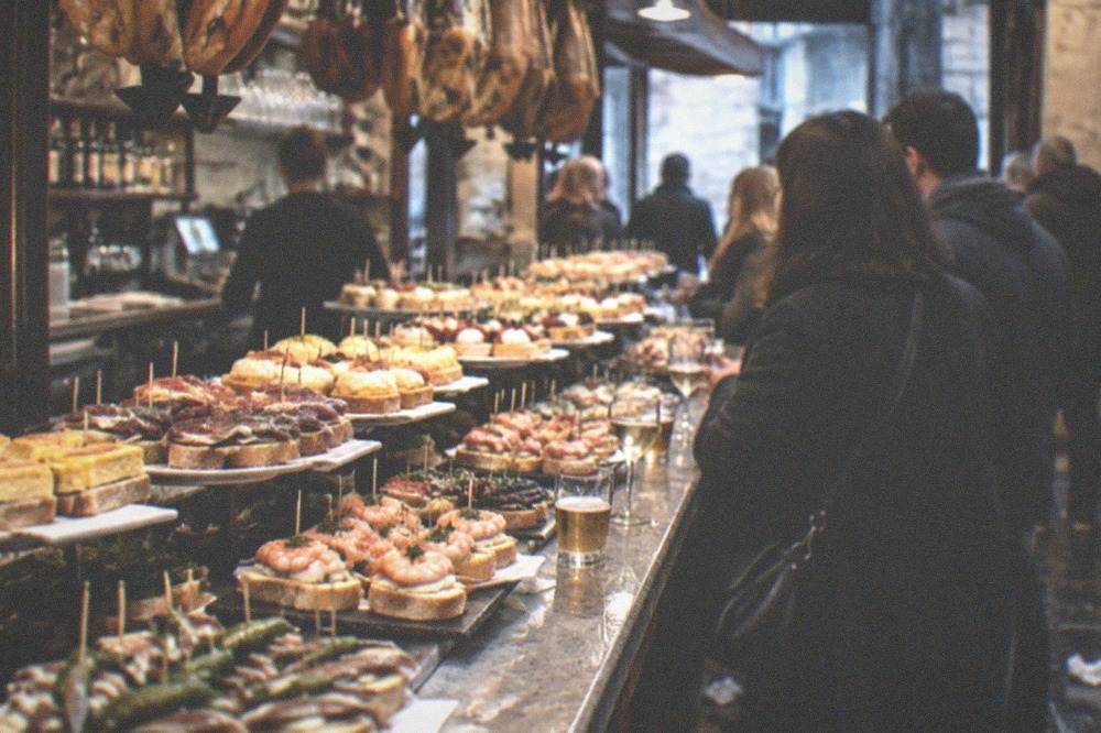 A pintxo bar counter in San Sebastián with small skewered and open-faced bites on display